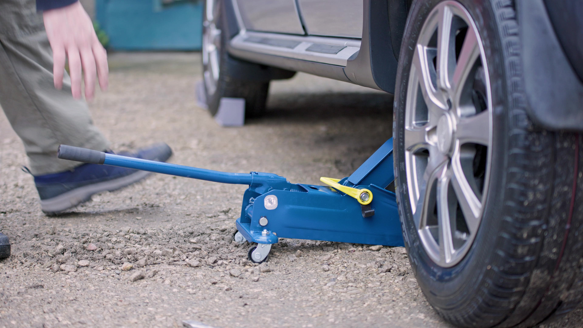 Használt gumiabroncs cseréje során autó emelése hidraulikus emelővel, kerékcsere előkészítése